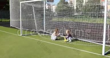 小女孩在足球球门后面的场地上玩软玩具